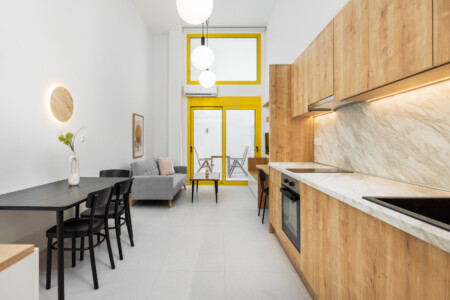 halu Modern kitchen and dining area with wooden cabinets and a marble countertop Black dining table with chairs and a cozy sofa Bright and spacious interior design