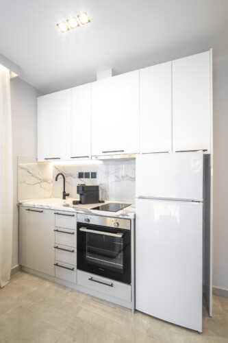 Modern one-bedroom apartment with stylish living room, fully equipped kitchen, private balcony, and contemporary design for a comfortable stay in Thessaloniki.