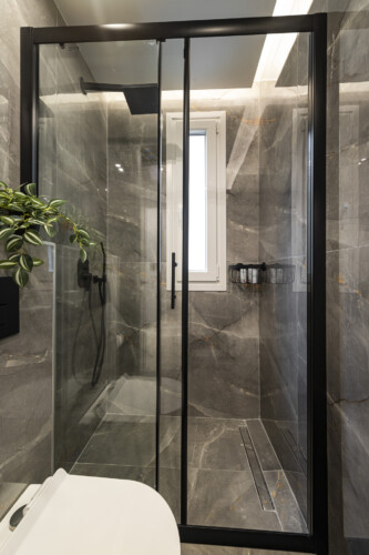 Modern one-bedroom apartment with stylish living room, fully equipped kitchen, private balcony, and contemporary design for a comfortable stay in Thessaloniki.