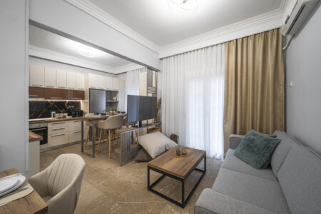 Modern three-bedroom apartment with stylish living room, fully equipped kitchen, balcony, and contemporary design for a comfortable stay in Thessaloniki.