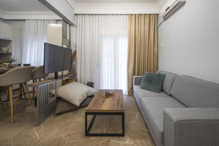 Modern three-bedroom apartment with stylish living room, fully equipped kitchen, balcony, and contemporary design for a comfortable stay in Thessaloniki.