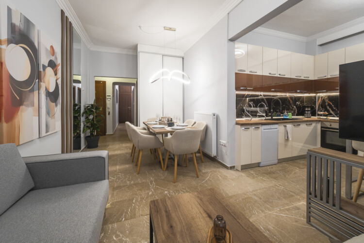 Modern three-bedroom apartment with stylish living room, fully equipped kitchen, balcony, and contemporary design for a comfortable stay in Thessaloniki.