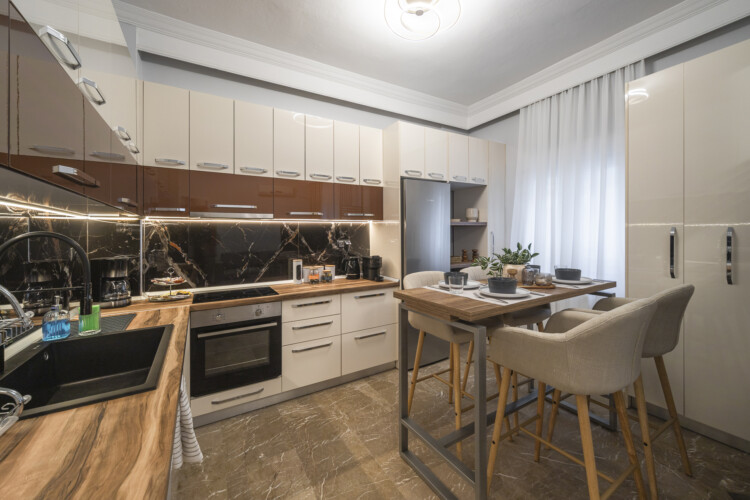 Modern three-bedroom apartment with stylish living room, fully equipped kitchen, balcony, and contemporary design for a comfortable stay in Thessaloniki.