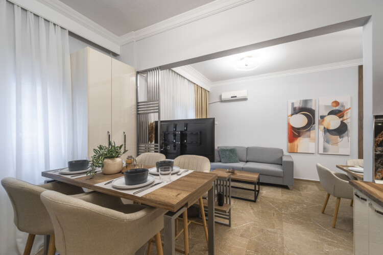 Modern three-bedroom apartment with stylish living room, fully equipped kitchen, balcony, and contemporary design for a comfortable stay in Thessaloniki.