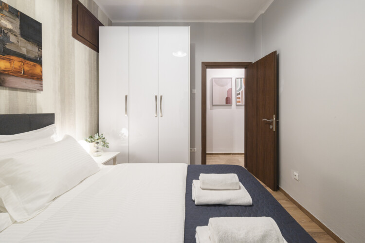 Modern three-bedroom apartment with stylish living room, fully equipped kitchen, balcony, and contemporary design for a comfortable stay in Thessaloniki.