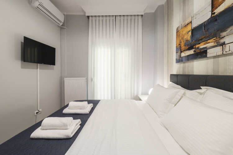 Modern three-bedroom apartment with stylish living room, fully equipped kitchen, balcony, and contemporary design for a comfortable stay in Thessaloniki.