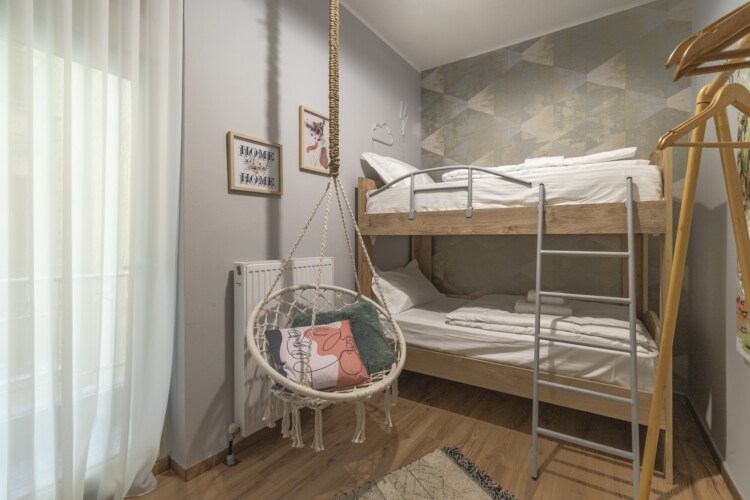 Modern three-bedroom apartment with stylish living room, fully equipped kitchen, balcony, and contemporary design for a comfortable stay in Thessaloniki.