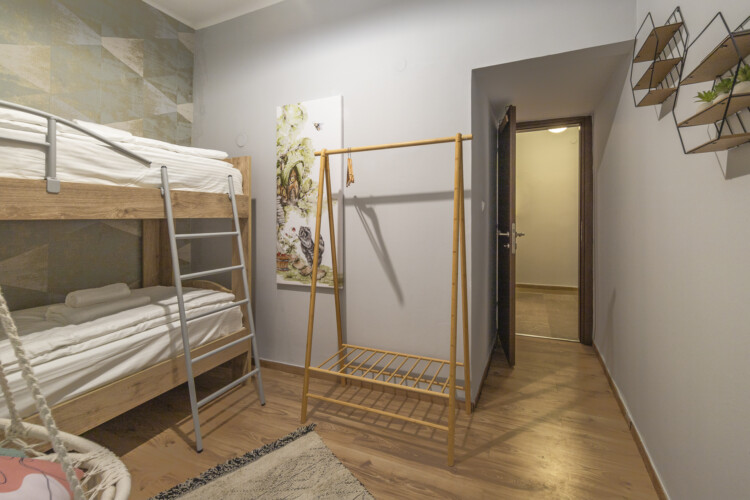 Modern three-bedroom apartment with stylish living room, fully equipped kitchen, balcony, and contemporary design for a comfortable stay in Thessaloniki.