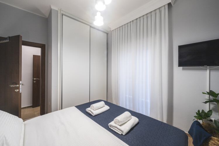 Modern three-bedroom apartment with stylish living room, fully equipped kitchen, balcony, and contemporary design for a comfortable stay in Thessaloniki.