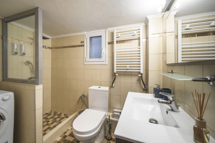 Modern three-bedroom apartment with stylish living room, fully equipped kitchen, balcony, and contemporary design for a comfortable stay in Thessaloniki.