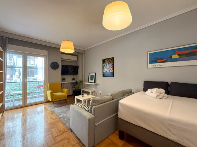 Modern one-bedroom apartment in the center of Thessaloniki with stylish living space, comfortable bed, and capacity for up to four guests.