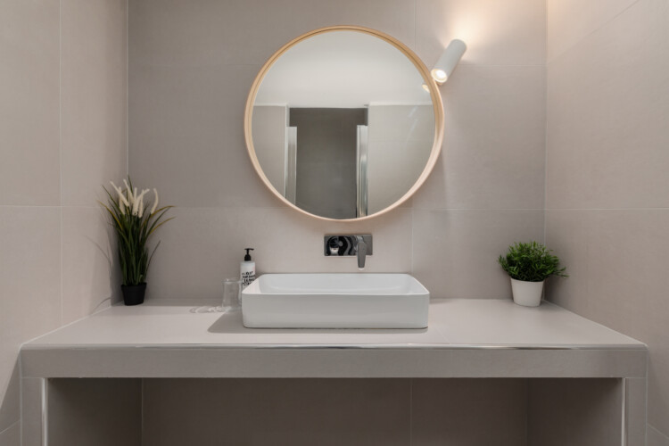 Modern bathroom with elegant marble-style tiles, a glass shower, fresh towels, and a washing machine. Bright and stylish, designed to offer both comfort and practicality during your stay.