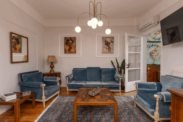 Halu! Cozy living room with blue velvet furniture and artistic decor. Soft lighting highlights the warm atmosphere. Perfect space for relaxation and gatherings.