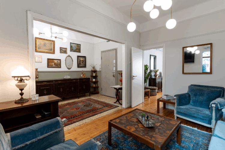 halu! Cozy living room with blue sofas and a wooden coffee table complemented by elegant lighting and artwork on the walls creating a warm and inviting atmosphere