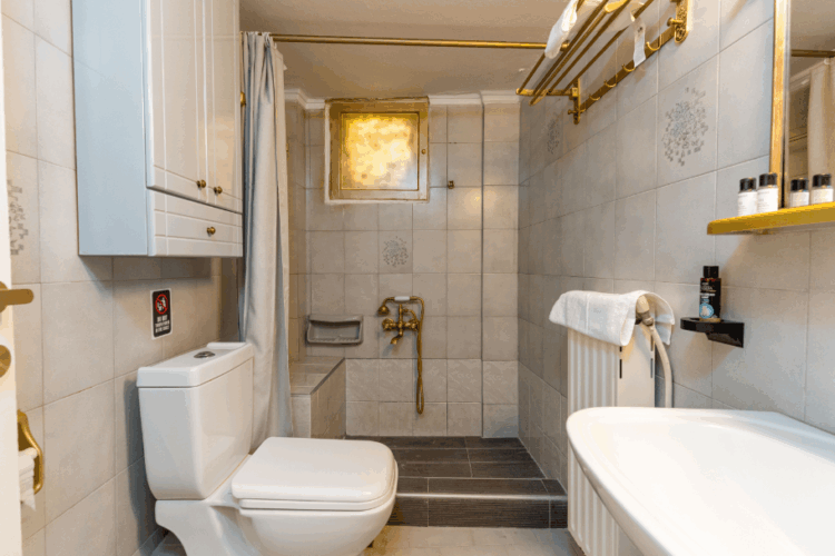 Halu! Elegant bathroom featuring a modern white toilet, sleek sink, and luxurious shower with golden fixtures, creating a clean and sophisticated ambiance.