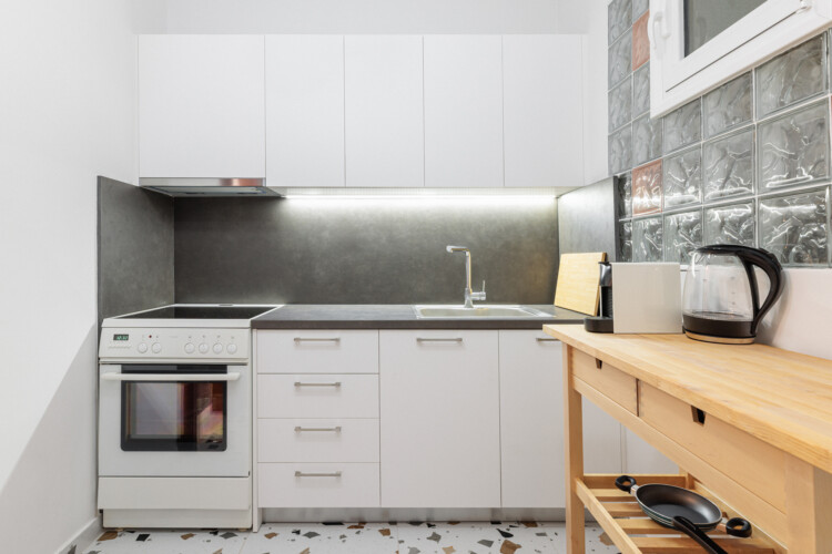 Modern fully equipped kitchen with stove, oven, sink, and storage space. Includes essentials like a kettle and coffee maker, making it ideal for preparing meals and enjoying a comfortable stay.