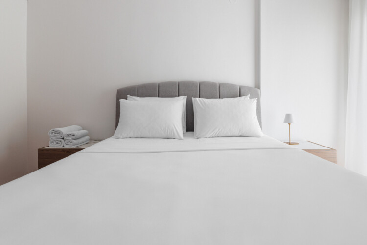 Bright and minimal bedroom with a queen-size bed, fresh white linens, and modern wooden bedside tables. A calm and inviting space designed for comfort and relaxation during your stay.