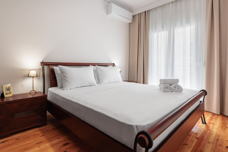 Bright and minimal bedroom with a queen-size bed, fresh white linens, and modern wooden bedside tables. A calm and inviting space designed for comfort and relaxation during your stay.