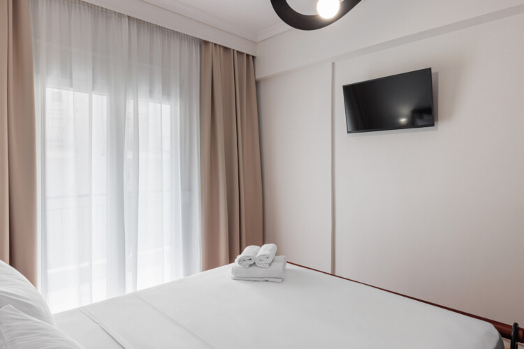 Cozy bedroom with a queen-size bed, fresh linens, and soft lighting. Features a large wardrobe, bedside tables, and a flat-screen TV, creating a comfortable and relaxing space for a restful stay.