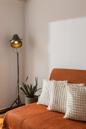 halu! Cozy living room with a modern floor lamp and a comfortable sofa. Neutral tones and textured pillows create a warm and inviting atmosphere perfect for relaxation