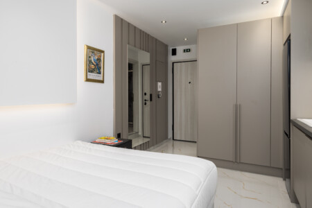 halu! Modern bedroom featuring a cozy white bed spacious wardrobe and minimalist decor ideal for a relaxing atmosphere with soft lighting and elegant furnishings