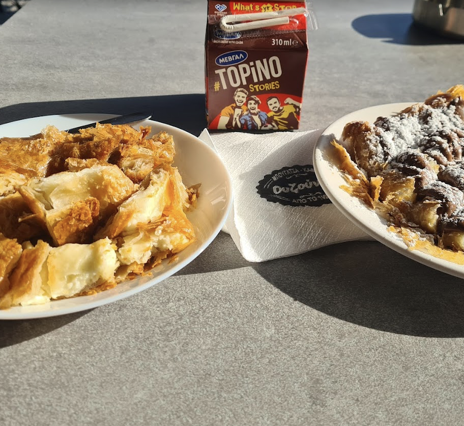 Halu! Enjoy a delightful breakfast spread with crispy puff pastry on one plate and sweet pastry drizzled with chocolate on another, accompanied by a chocolate drink.