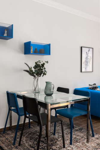 halu! Modern dining area with glass table and blue chairs elegant decor and art on the wall stylish interior design for a contemporary living space