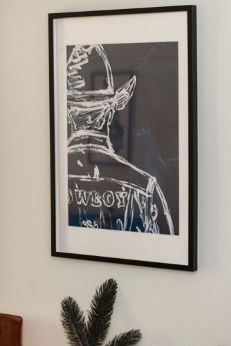 Halu! Framed artwork depicting a cowboy from behind in a rustic style by halu! Featured in Indiana decor creating a western-inspired interior atmosphere.