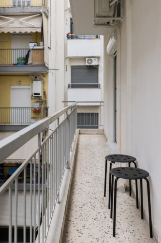 Halu! Discover Indiana by halu with a serene balcony view featuring modern black stools and urban architecture ideal for relaxation and unwinding in style.