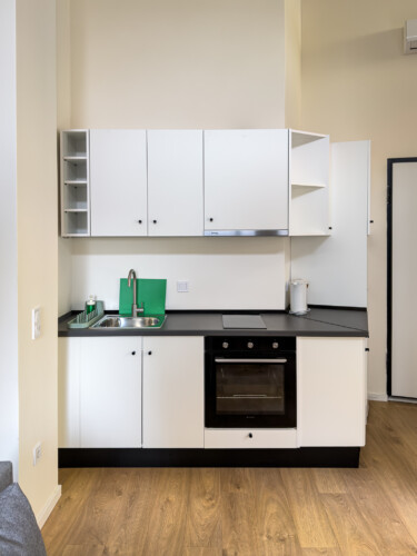 halu! Modern kitchenette featuring sleek white cabinets minimalist design black countertop stainless steel sink integrated oven ideal for compact practical living spaces