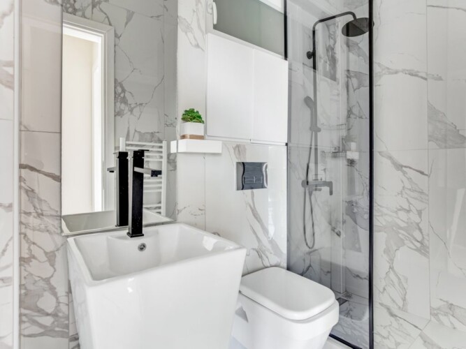 halu! Modern bathroom in Verde premium apartments featuring elegant marble tiles, a sleek black shower fixture, and a minimalistic white sink. Perfect urban living space.