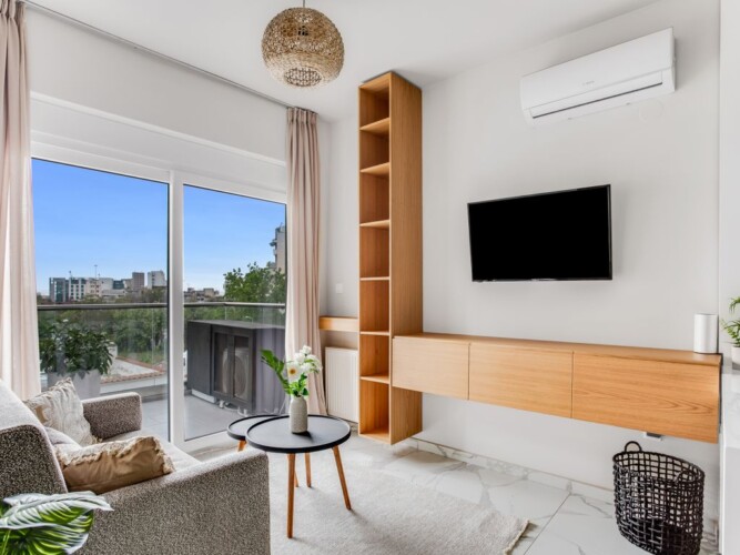 Halu! Modern living room with large window view stylish furniture wall-mounted TV wooden shelving cozy decor indoor plant and ambient lighting creating a relaxing space.