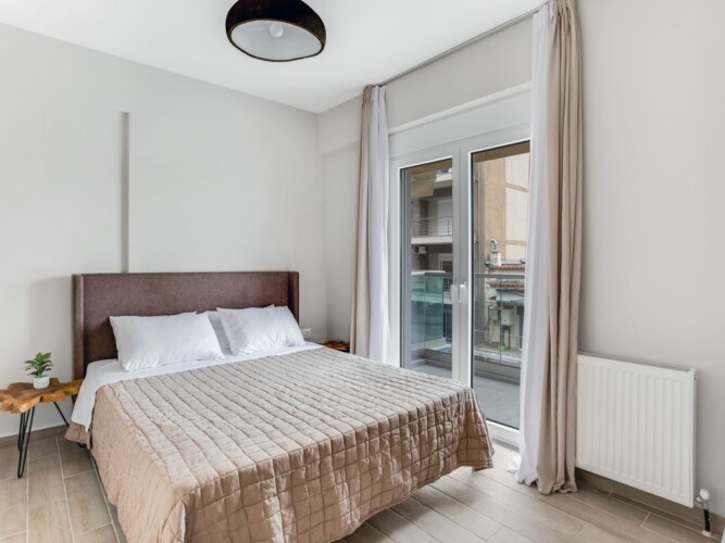 Halu! Experience luxury living at Verde Premium Apartments with elegant bedroom design featuring a cozy bed and large window for natural light and city views.