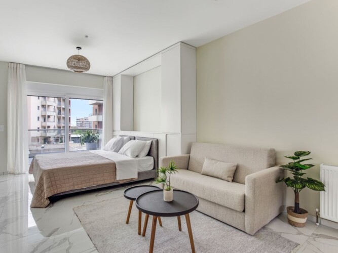 Halu! Experience luxury living at Verde Premium Apartments featuring a modern and spacious interior with a cozy sofa elegant bed and large window for natural light.