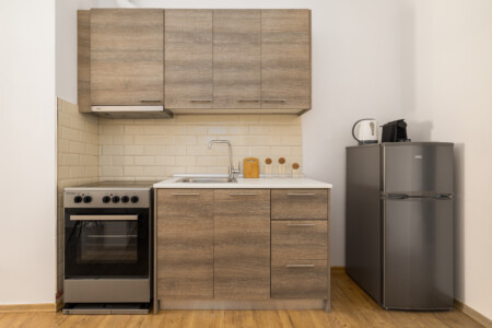 Halu! Discover the modern kitchenette at Ourania Lofts and Suites in Thessaloniki featuring sleek wood cabinets stainless steel appliances and contemporary design.