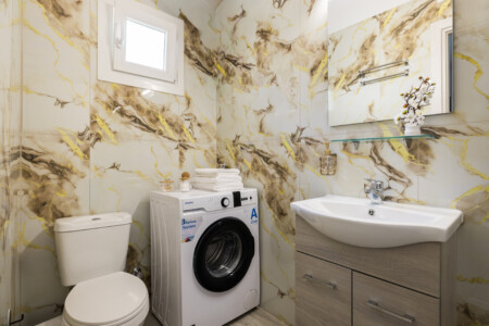 Halu! Modern bathroom at Ourania Lofts and Suites in Thessaloniki featuring elegant decor with a washing machine and vanity offering comfort and convenience.