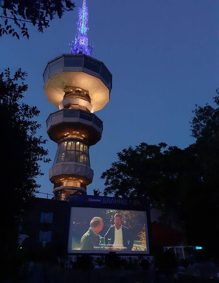 Ellinis Summer Cinema in Thessaloniki with the illuminated OTE Tower rising behind the outdoor screen.