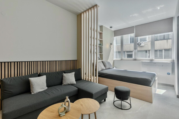 Halu! Discover Odyssey - Premium SKG suites in Ladadika. This modern suite in the city center features chic decor, a cozy seating area, and a spacious bed by the window.