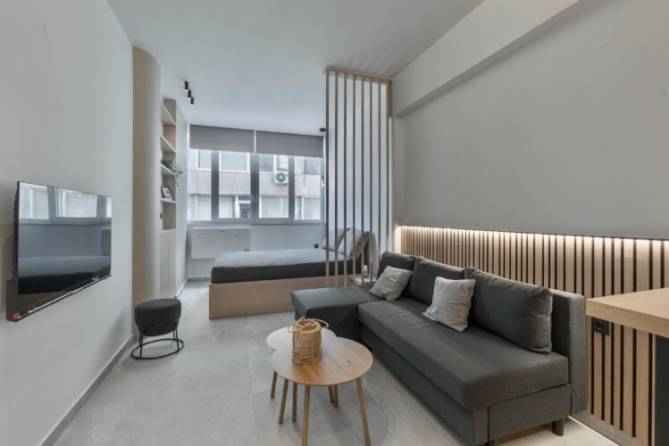 Halu! Discover modern elegance at Odyssey - Premium SKG suites in Ladadika Center featuring a stylish living area with sleek furniture and soft lighting for relaxation.