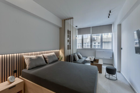 halu! Experience luxury at Odyssey - Premium SKG suites in Ladadika Center. Modern and stylish room design with comfortable bed and seating area for a perfect stay.