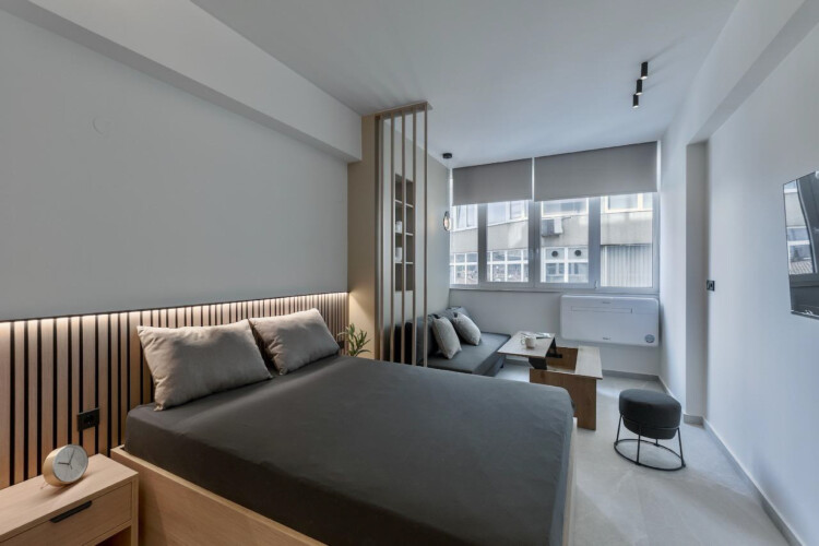 halu! Experience luxury at Odyssey - Premium SKG suites in Ladadika Center. Modern and stylish room design with comfortable bed and seating area for a perfect stay.